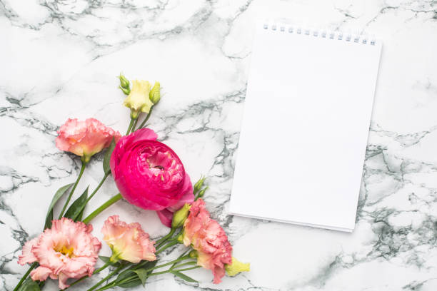 istock Notebook and pink flower bouquet on marble background 1267809346