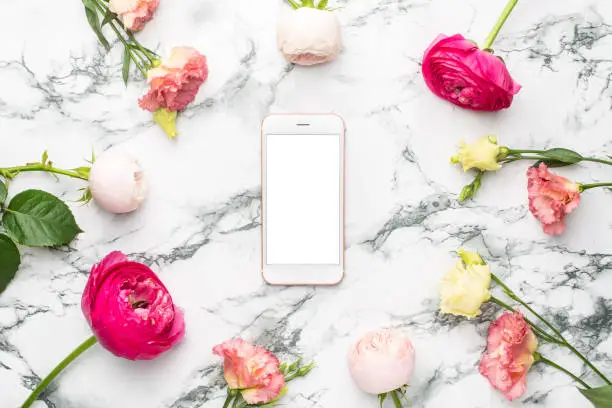 Mobile phone, Ranunculi pink flower and white flower bouquet on marble background top view