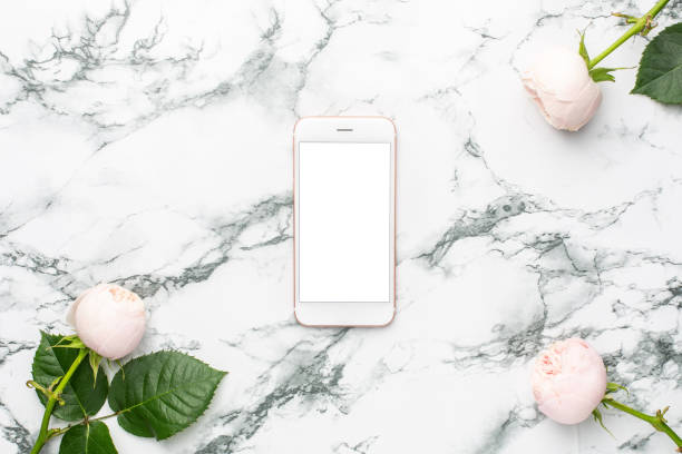 istock White roses with mobile phone on white and black marble background with copyspace 1267809353