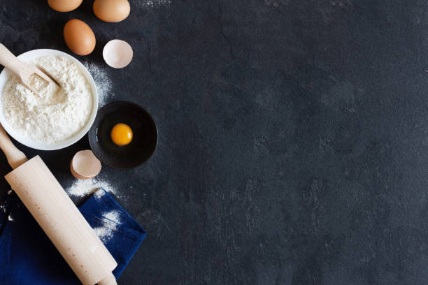 istock Ingredients and tools for dough preparation on black background top view. 1267811513