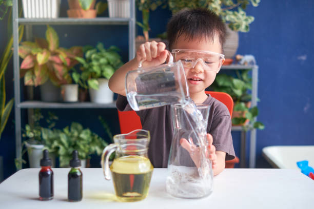 Asian school kid studying science, making DIY Lava Lamp Science Experiment, Kid-friendly fun and easy science experiments at home concept Happy little Asian school kid studying science, making DIY Lava Lamp Science Experiment with oil, water and food coloring, Kid-friendly fun and easy science experiments at home concept montessori education photos stock pictures, royalty-free photos & images