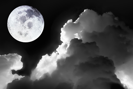 Image of bright full moon in dark sky with dramatic of light and texture on soft cloudscape in black and white for meteorology background.