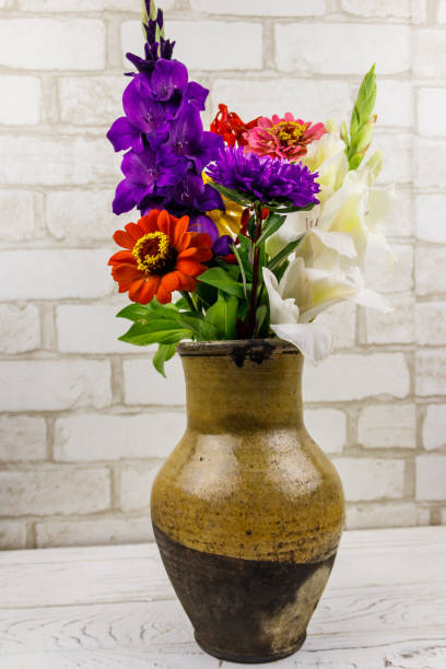 흰색 벽돌 벽에 골동품 소박한 점토 용기에 꽃다발 - gladiolus bouquet vase purple 뉴스 사진 이미지