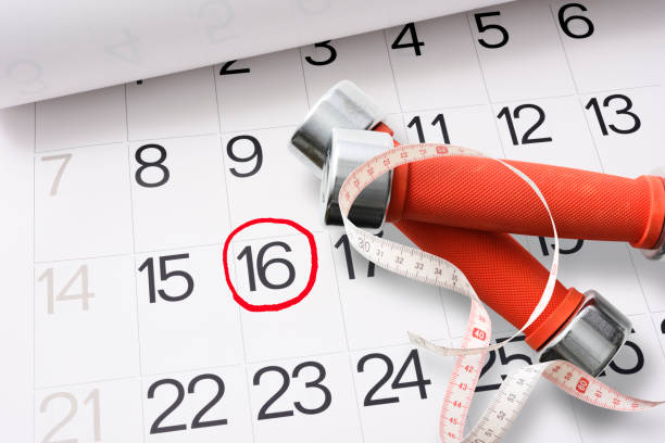 istock Red dumbbells with measuring tape on the calendar. 1267814518