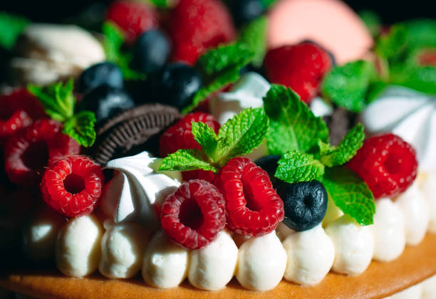Fruit cake. Cake decorated with berries on a wooden stand on a black background