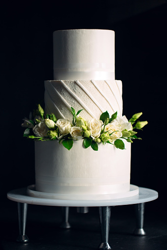 Three tier wedding cake with roses and greenery