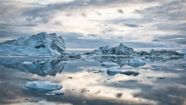 Greenland Icebergs Sunset Cloudscape Panorama Greenland Arctic Icebergs Sunset Twilight Panorama. Large arctic Iceberg drifting on the polar waters under moody sunset skyscape, cloudscape mirroring in the calm water. Arctic Ocean, Illulissat, Greenland, Denmark, North Polar Region climate change photos stock pictures, royalty-free photos & images