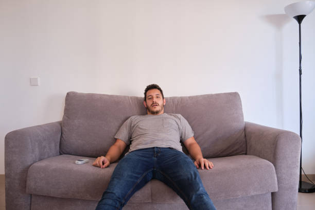 istock Young man sitting on a sofa watching television absorbed with his mouth opened 1267828129
