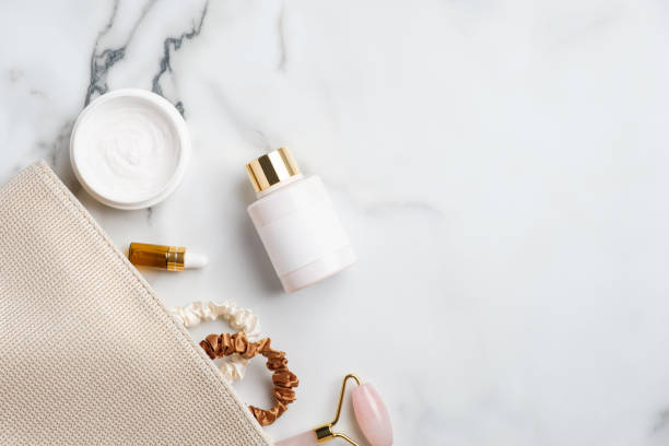istock Bathroom cosmetic bag with moisturizer cream, lotion, face massage roller, essential oils bottles and female accessories on marble desk. Beauty products set. Flat lay, top view. 1267849690