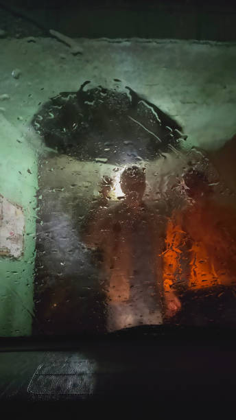 istock Two people with umbrella in the rain through car window at night. 1267849712