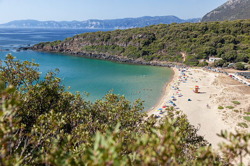 Osalla Beach with many tourists swimming, taking sunbath, relaxing, in Orosei Gulf seen from above next to Nuraghe Galunie