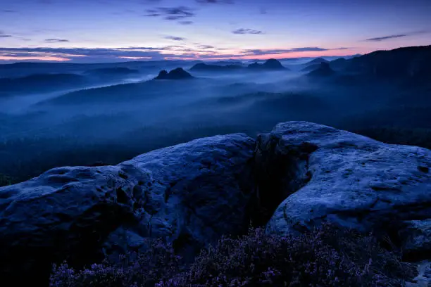 Photo of Kleiner Winterberg, beautiful morning view over sandstone cliff into deep misty valley in Saxony Switzerland, landscape in Germany. Fog and beautiful backlight. Stone hill sunset. Rocky landscape in Europe.