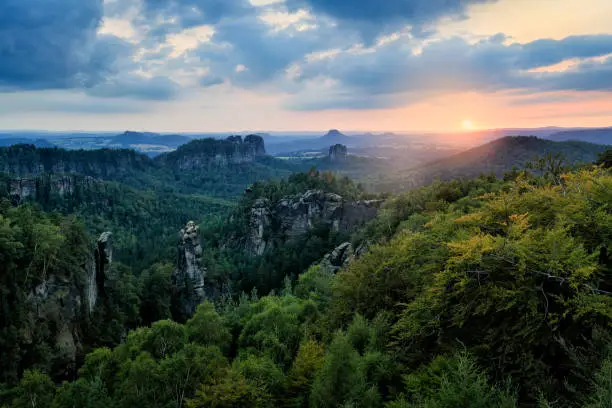 Photo of Carolafelsen in Germany, beautiful evening view over sandstone cliff into deep misty valley in Saxony Switzerland. Sandstone peaks increased from foggy background. Evening landscsape in the wild nature.