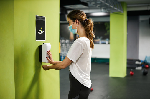 Woman using hand sanitizer in the gym.