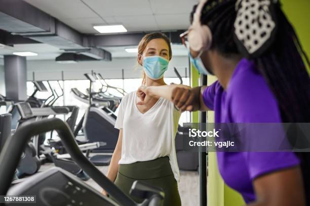 Two Women Greeting With Elbow Bump In The Gym During Coronavirus Pandemic Stock Photo - Download Image Now