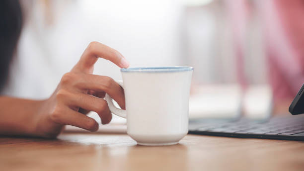 istock Closeup image of woman’s hand holding white mug while sitting at office desk with tablet computer. 1267906100
