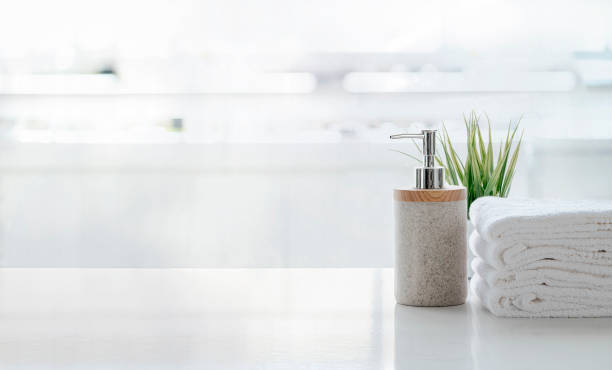 istock Ceramic shampoo, soap bottle and towels on counter over kitchen room background. White top table and copy space. 1267907515