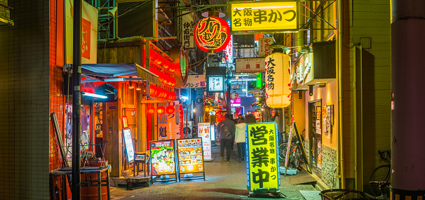 People in the quiet back streets of Dotonbori and Namba between the neon lit restaurants of this vibrant Osaka district, Japan.