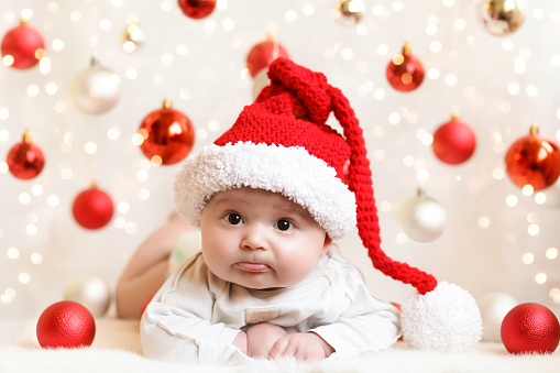 little boy wearing a Santa Claus hat on a background of Christmas balls