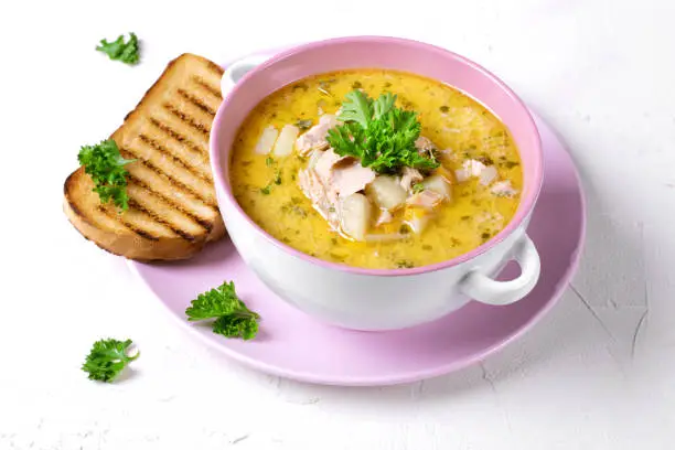 Soup with red fish and cream topped with fresh parsley served in the ceramic tureen