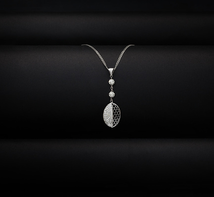 An elegant jewelry. White gold necklace on black background.