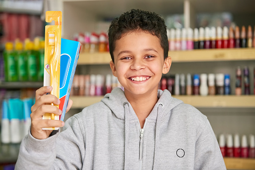 Portrait of a young boy holding new toothbrush and tooth paste at a store