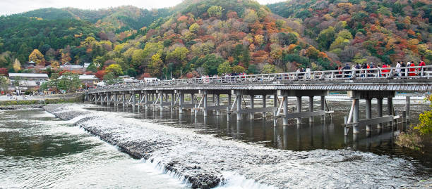 ponte togetsukyo com montanhas de folhas coloridas e rio katsura em arashiyama, marco e popular para atrações turísticas em kyoto, japão. outono temporada de outono, férias, férias e passeios turísticos - togetsu kyo bridge - fotografias e filmes do acervo