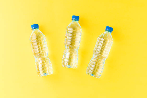 Mineral water in small plastic bottles on yellow background. Top view. Flat lay