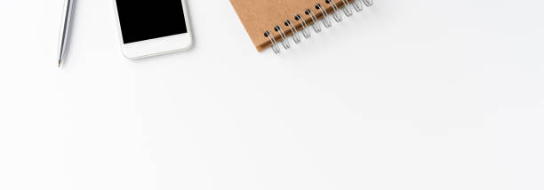 istock Modern workspace with mobile phone, notebook and pen. Office desktop concept. Banner 1267955971