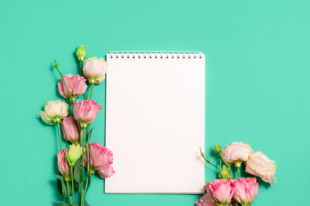 istock Blank notebook with pink flowers on green background 1267956167