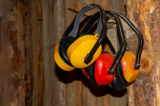The ear muffs hang from a nail on the log wall. Village sawmill. Health protection stock photo