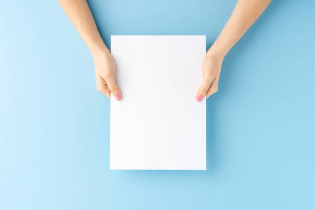 istock Female hands showing empty paper sheet on blue background. Close up 1267964560