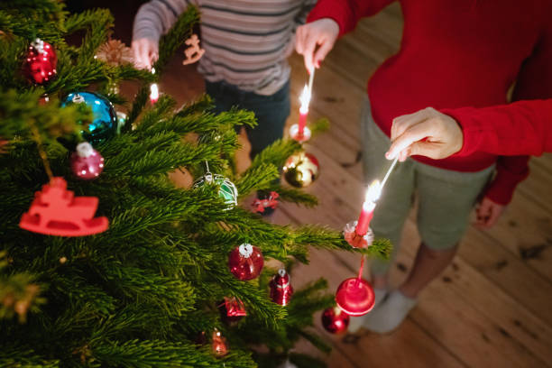 family lighting the candles of the christmas tree with matches - fire match women flame imagens e fotografias de stock