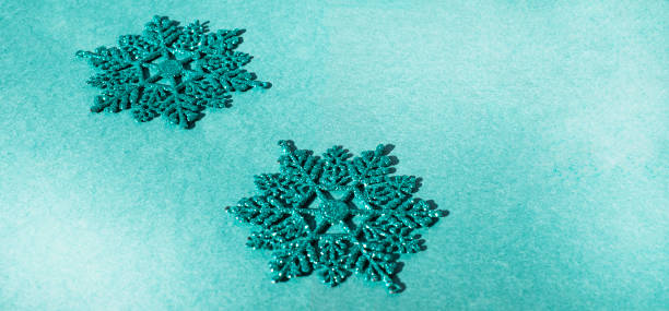 istock Two turquoise sparkling snowflakes on a turquoise background. Christmas banner. Copy space for text. 1267975926