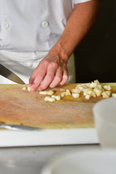 istock Male chef cutting potatoes with a kitchen knife on a cutting board 1267996505