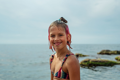 Smiling girl with colorful hair at the beach, happy summer vacation