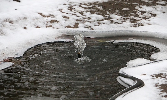 A closeup shot of a water fountain in a frozen snowy park