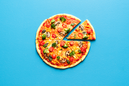 Pizza primavera top view on a blue table. Sliced vegetarian pizza isolated on a colored background