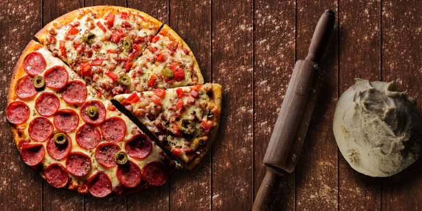 istock Pizza top view with cut slice and rustic wood background and space for text 1268012896