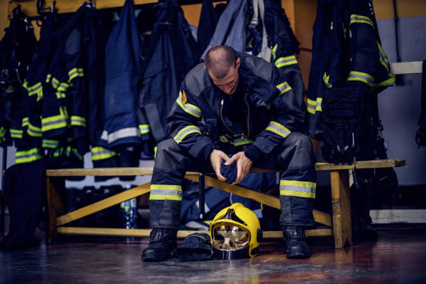 istock Young attractive fireman in protective uniform sitting in fire station and waiting for other firemen. He is prepared for action. 1268016950