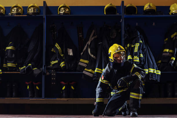 istock Brave young firefighter in protective uniform with helmet on head kneeling in fire station prepared for action. 1268017833