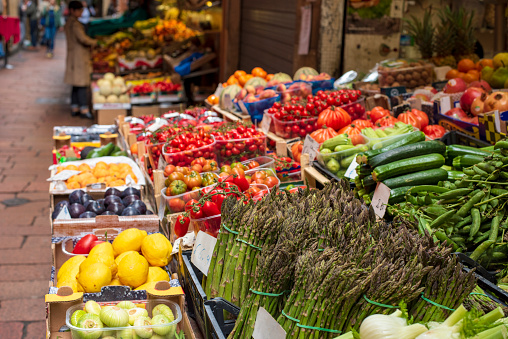 Traditional food market in the center of Bologna, Italy. Bundles of asparagus in the foreground.