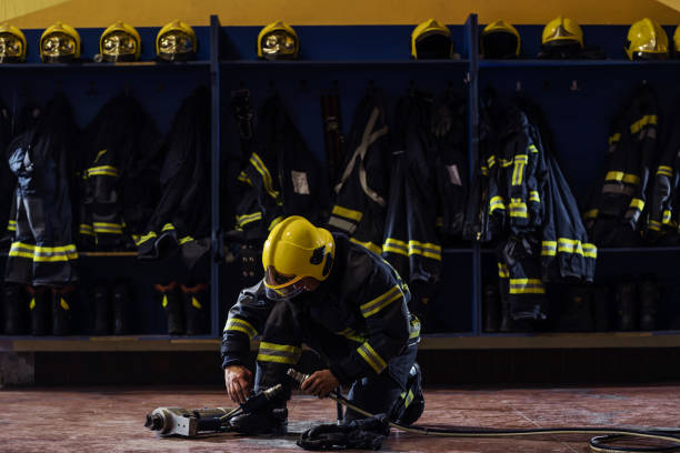 istock Fireman in protective uniform with helmet on head kneeling in fire station and preparing equipment for action. 1268019870