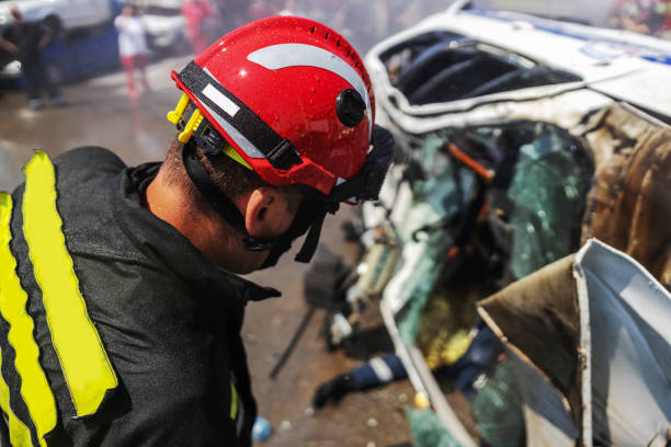 Firemen trying to release man from crashed car. There is a crashed cars in car accident.