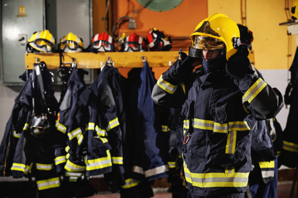 istock Fireman standing in fire station, putting helmet and preparing for action. 1268020750