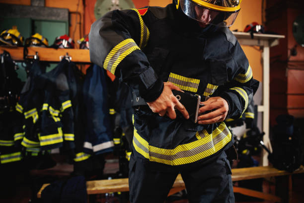 istock Fireman putting on protective uniform and preparing for action while standing in fire station. 1268021029