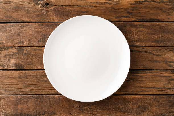 istock Overhead shot of empty white plate on rustic wooden table. Close up 1268021123