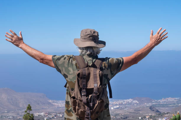 istock Rear view of a senior man with hat and backpack enjoying excursion in mountain range in Tenerife island - concept of summer vacation for an elderly active people 1268021922