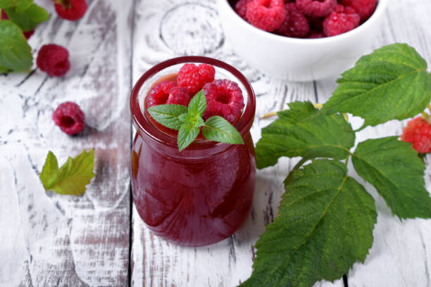 Raspberry jam in the glass jar Raspberry jam in the glass jar on the white wooden table raspberry jam stock pictures, royalty-free photos & images