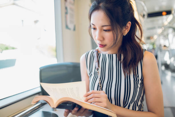istock asian woman reading book in subway train 1268023018